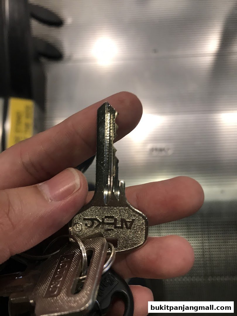 A hand holds a set of keys, one with the brand name 'ATEKG' visible.