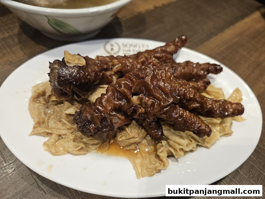 A plate of braised chicken feet served with beancurd skin and a bowl of soup.