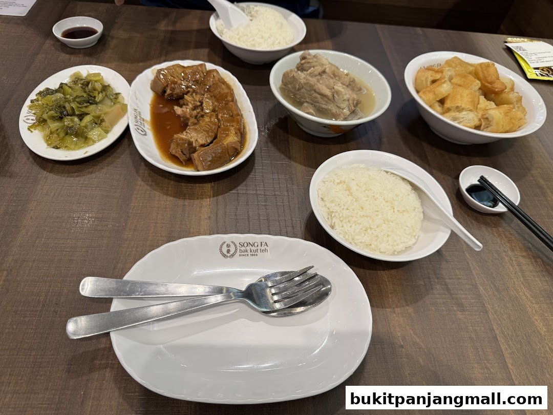 A table laden with various dishes from Song Fa Bak Kut Teh, including rice, braised pork, and pickled vegetables.