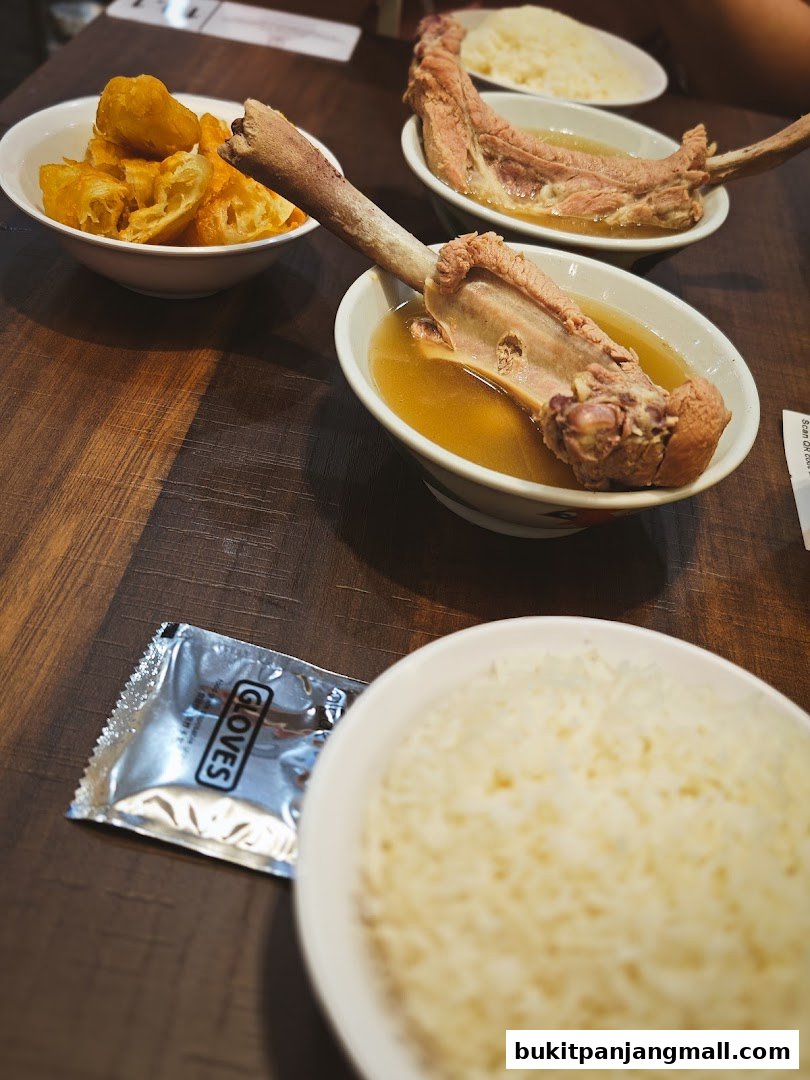 Bowls of bak kut teh with pork ribs, rice, and fried dough sticks.