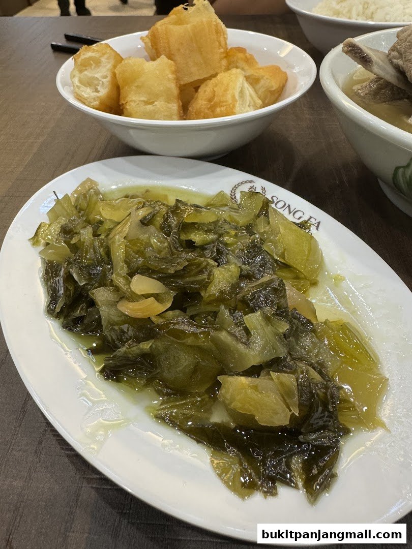 A plate of preserved mustard greens served with fried dough sticks and bak kut teh.