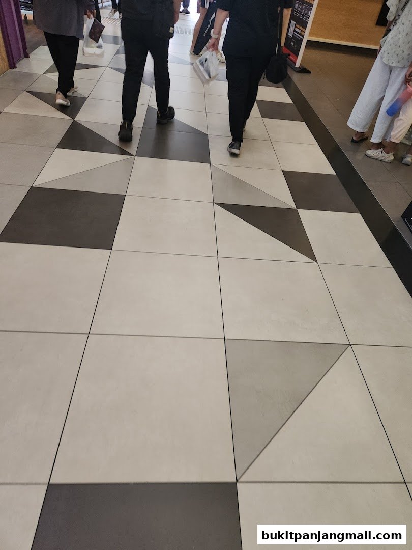 People walking on a patterned tiled floor in a shopping mall.