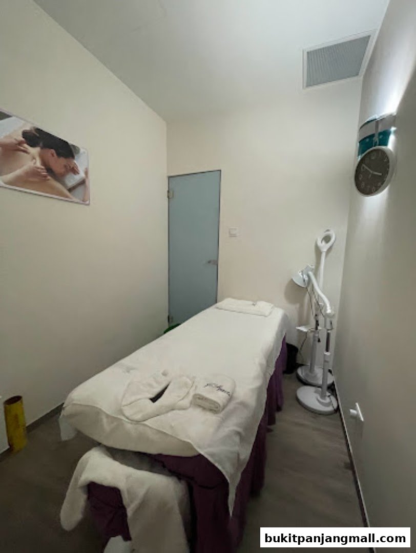 A treatment room with a massage bed, a picture of a massage, and spa equipment.