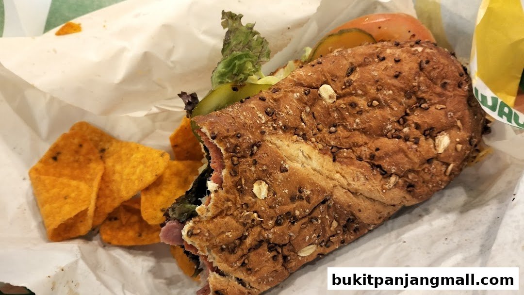A close-up of a Subway sandwich with chips on the side.