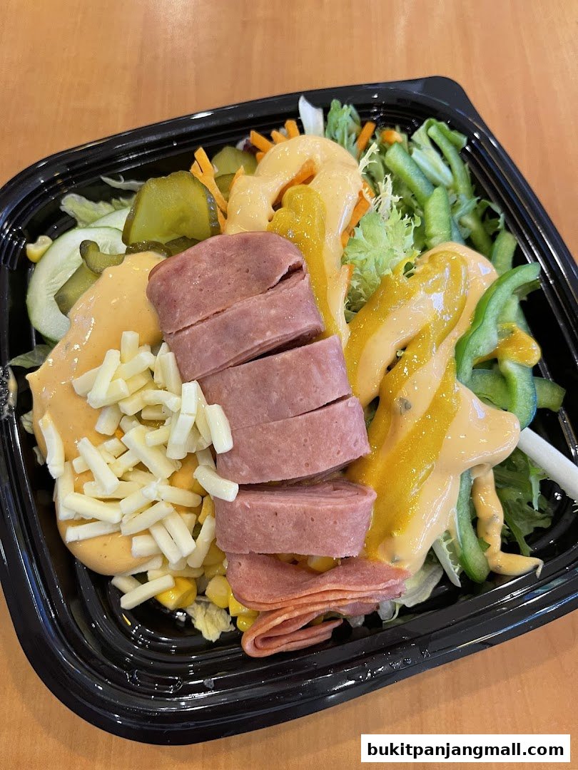 A Subway salad with sliced meat, cheese, pickles, corn, and dressing.