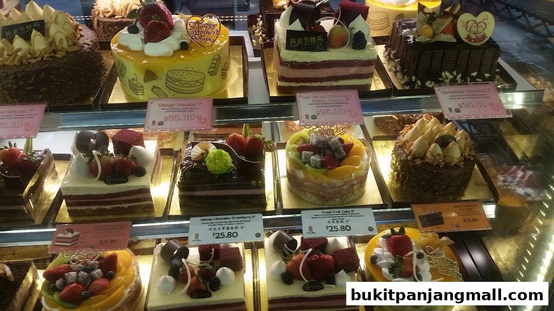A display case filled with various beautifully decorated cakes, including fruit and chocolate varieties.