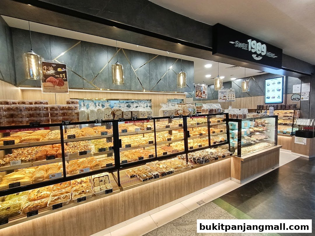 A wide display of freshly baked pastries and bread in a modern bakery.