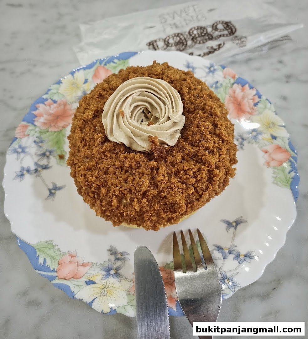A close-up of a delicious pastry with crumb topping and cream swirl on a floral plate.