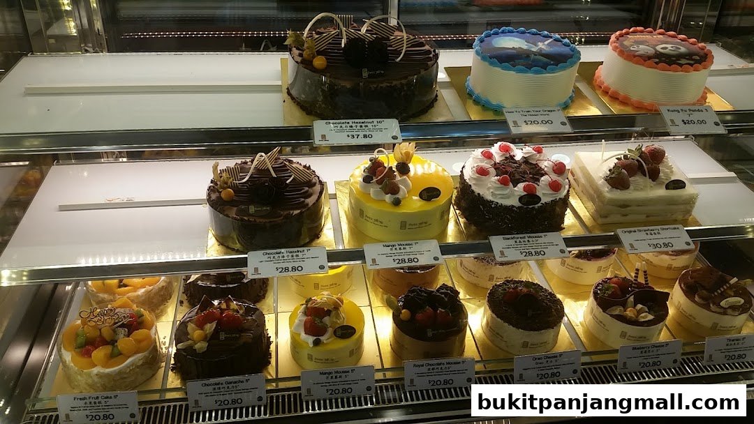 A display case filled with various beautifully decorated cakes and pastries from Swee Heng Bakery.