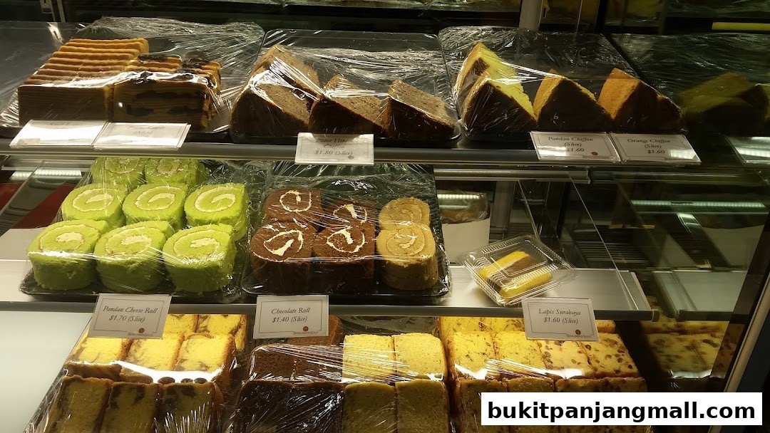 A display case filled with various cakes and pastries, including swiss rolls and chiffon cakes.