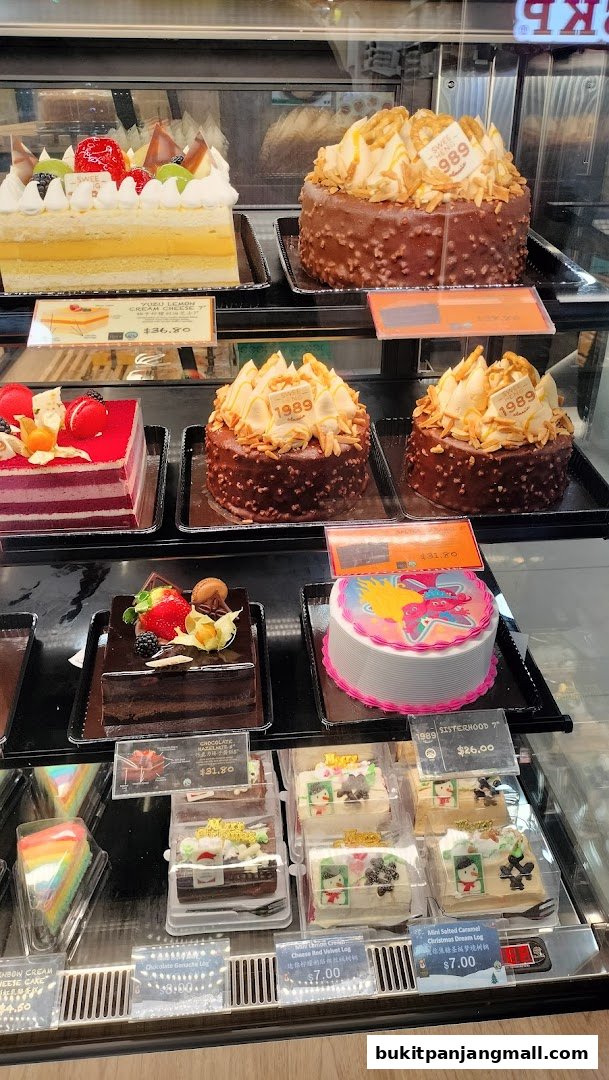 A display case filled with various cakes and pastries, including fruit tarts and chocolate cakes.