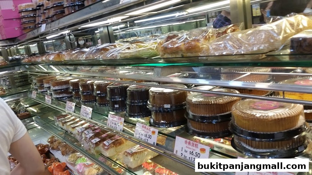 A display of various cakes and pastries in a bakery, with prices visible on some items.