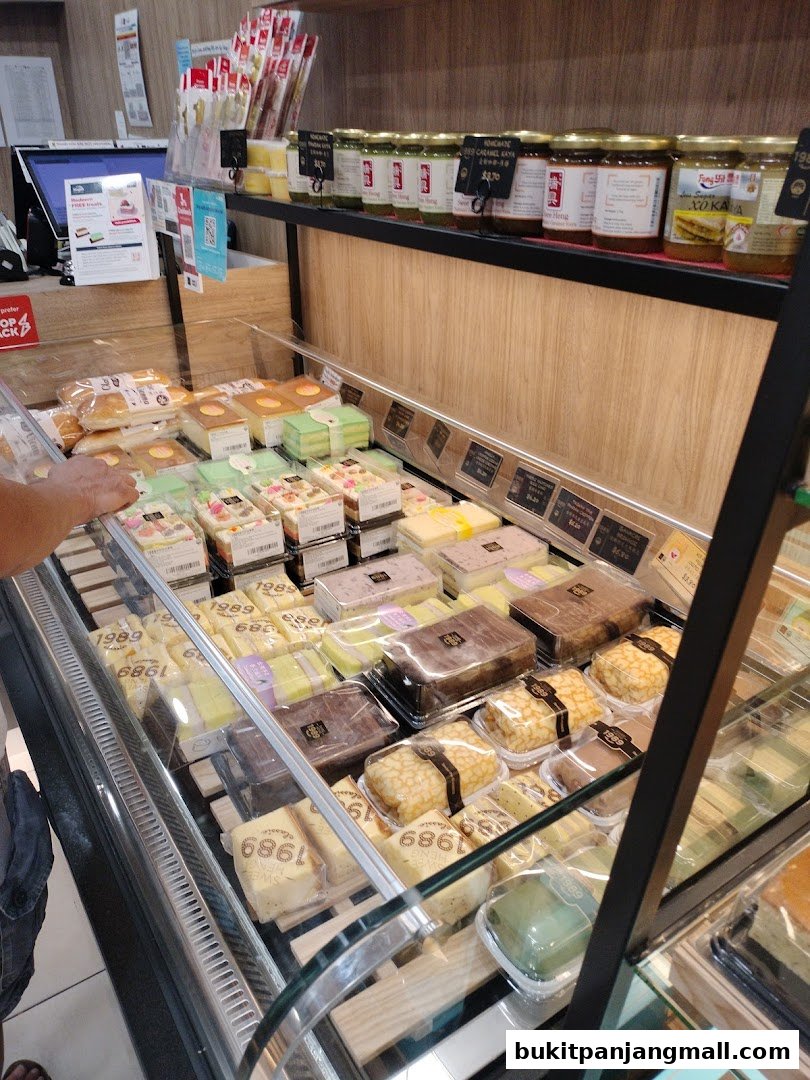 A display case filled with various cakes, pastries, and jars of kaya at Swee Heng Bakery.