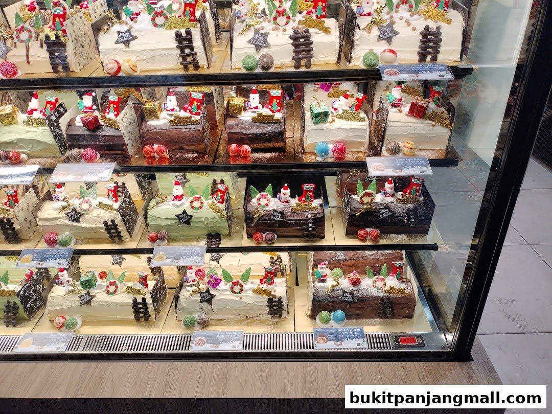 A display case filled with various Christmas-themed log cakes decorated with Santa, stockings, and festive ornaments.