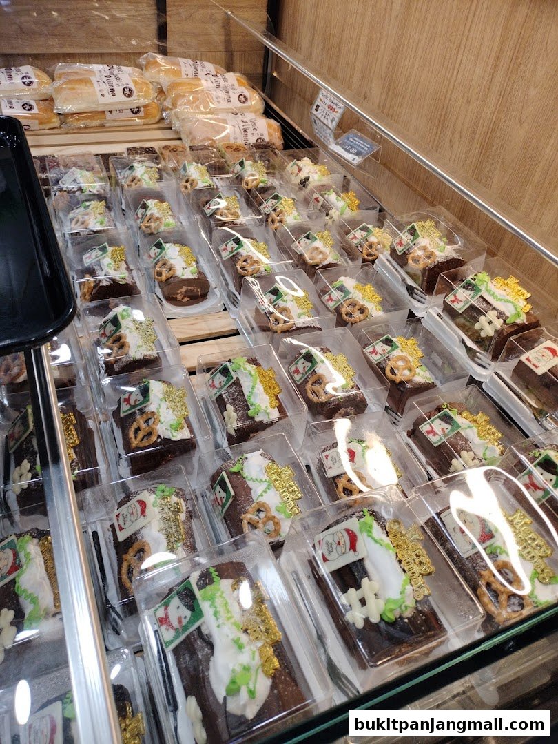 A display of individually packaged chocolate log cakes with festive Christmas decorations.