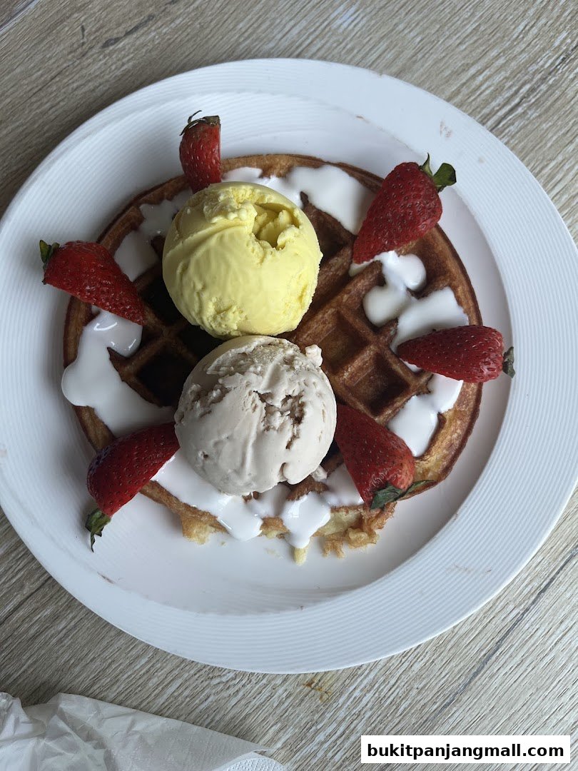 A delicious waffle topped with two scoops of ice cream and fresh strawberries.