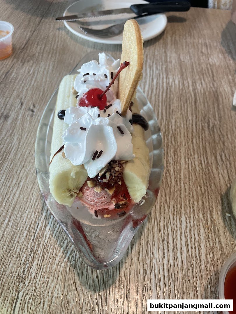 A delicious banana split dessert with ice cream, whipped cream, cherry, and a cookie.