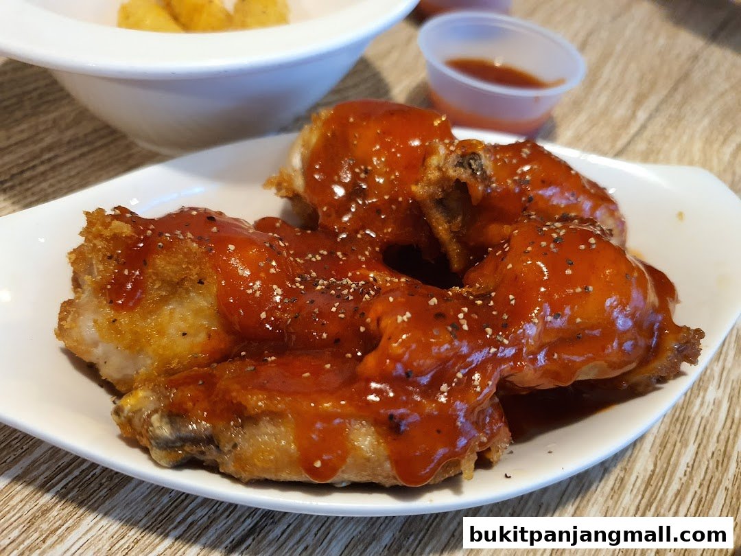 A plate of delicious chicken wings coated in a glossy sauce and sprinkled with pepper.