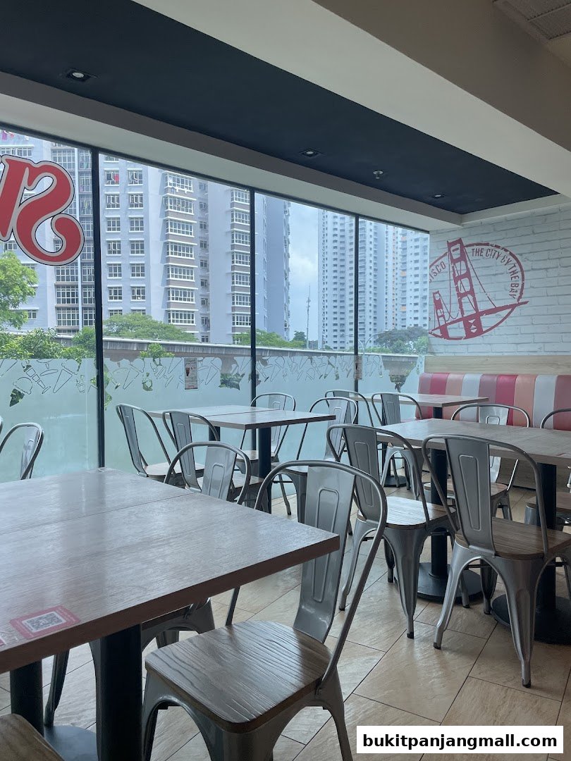 Interior view of Swensens restaurant with tables and chairs, overlooking city buildings.