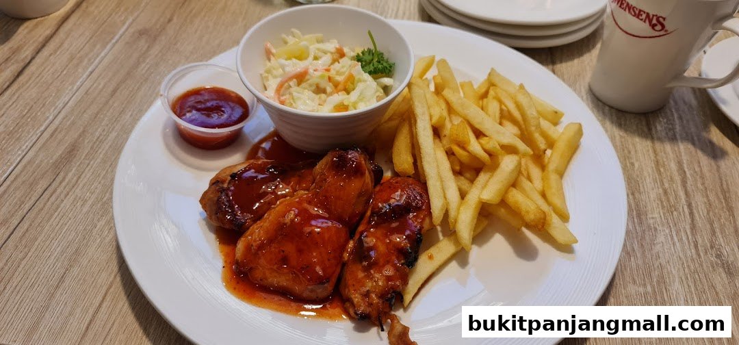 A plate of glazed chicken wings with fries, coleslaw, and a side of sauce.