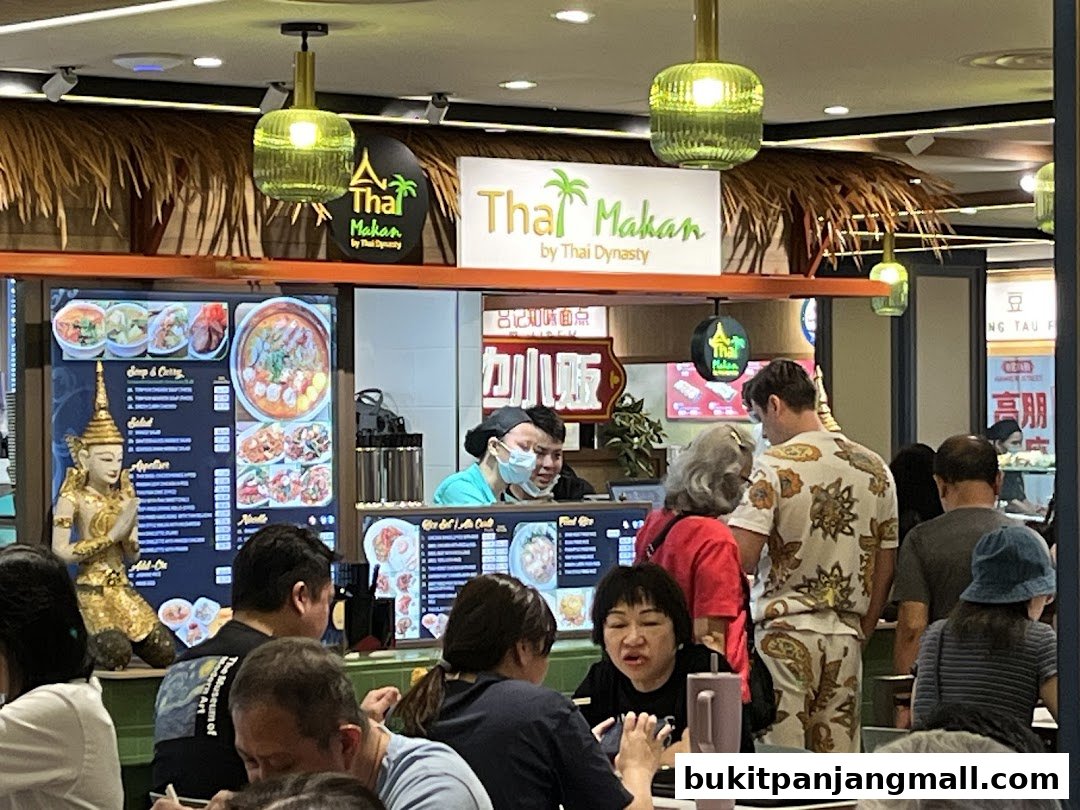 People ordering food at a Thai restaurant counter with a menu display.