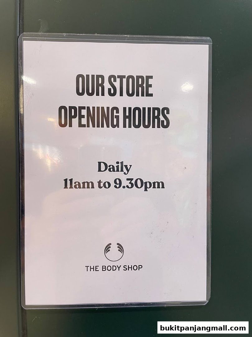 A sign displaying The Body Shop's daily opening hours from 11 am to 9:30 pm.