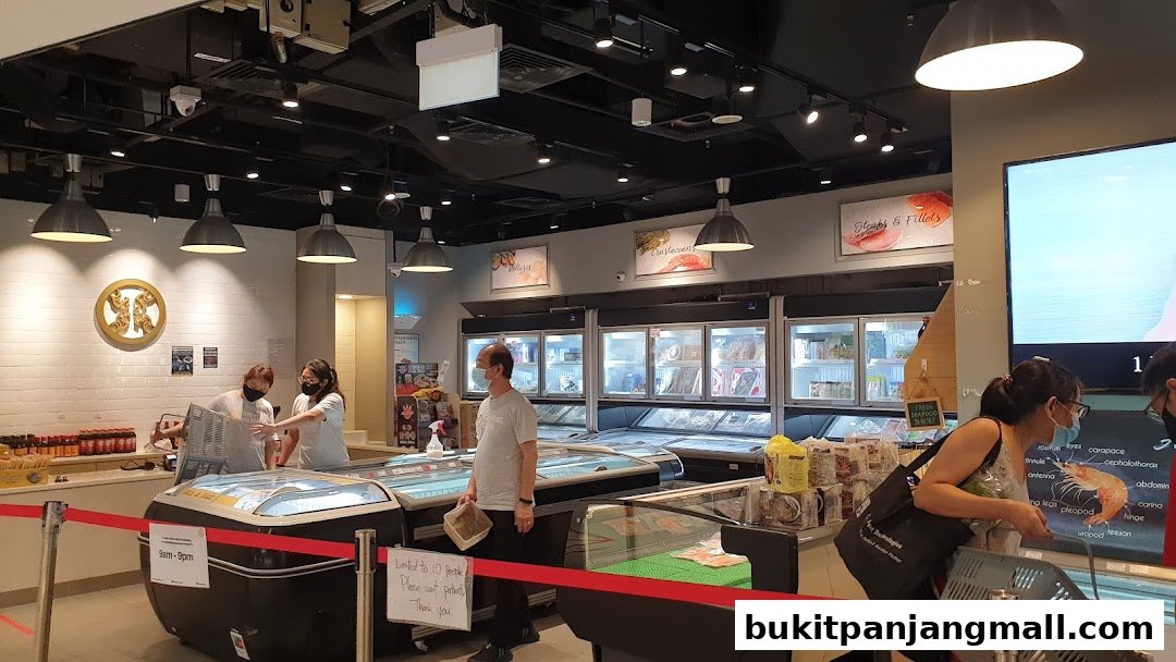 Interior of a seafood market with customers and staff near refrigerated display cases.