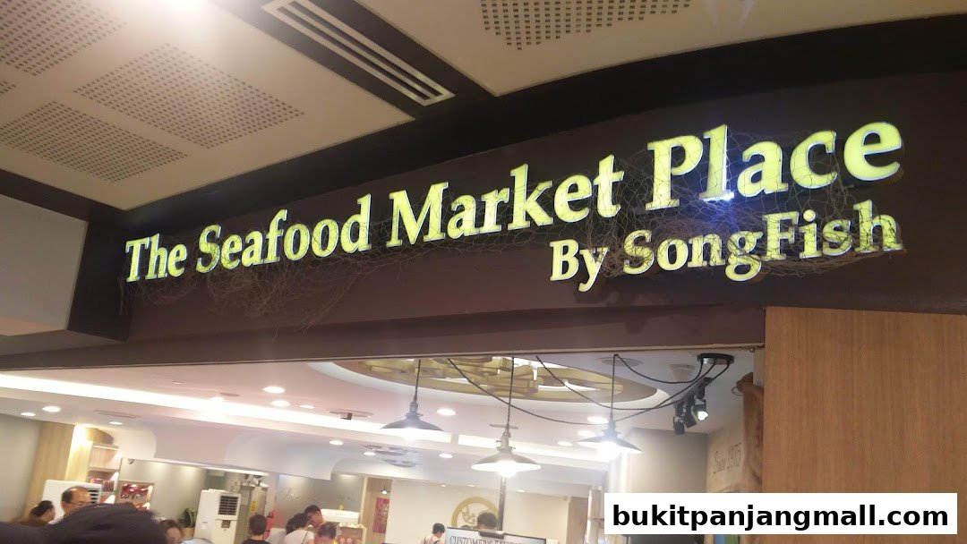 A brightly lit sign for 'The Seafood Market Place By Song Fish' hangs above an entrance.
