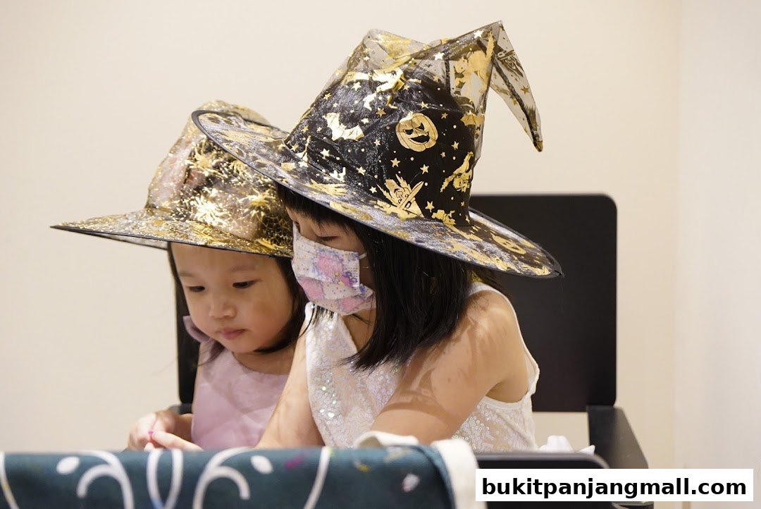 Two young girls wearing festive witch hats, one with a face mask, engaged in an activity.
