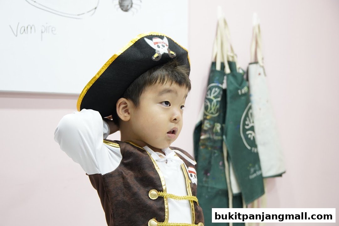 A young boy dressed as a pirate adjusts his hat in front of a whiteboard and aprons.