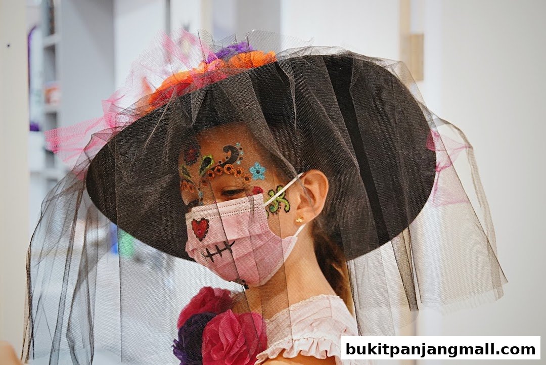 A child with face paint and a mask, wearing a decorative hat with a veil.