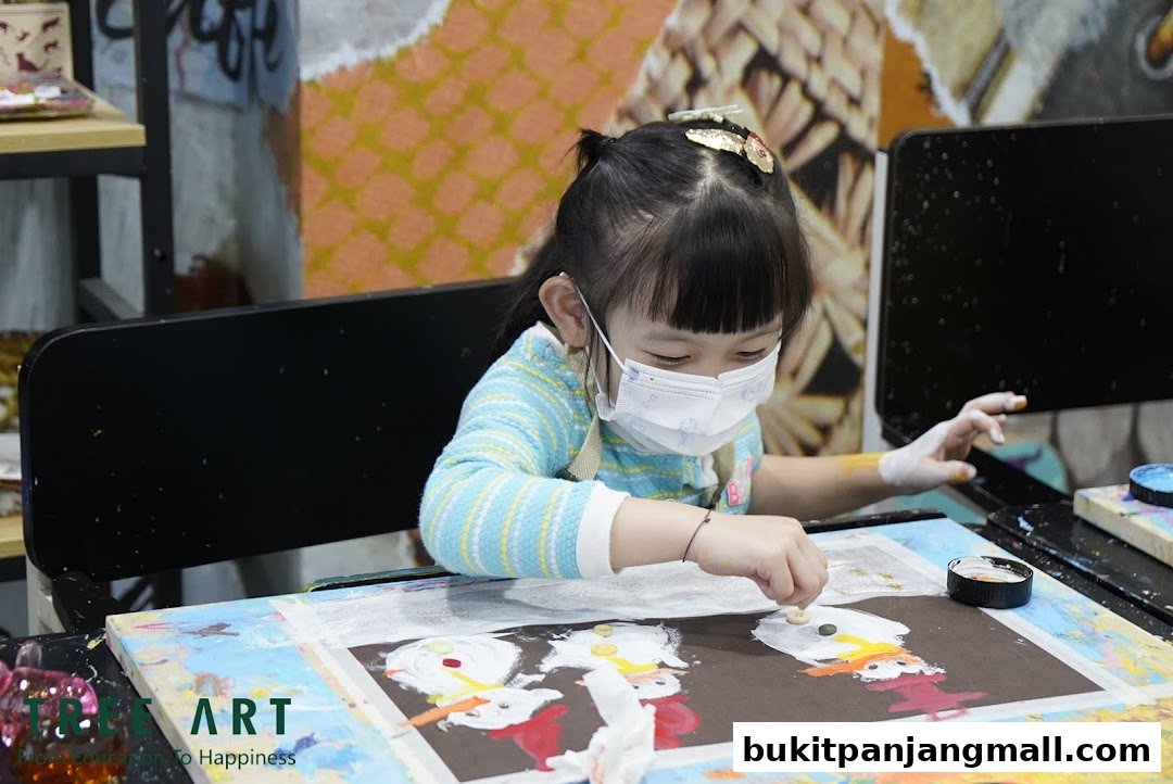 A young child wearing a mask is focused on an art project, painting.