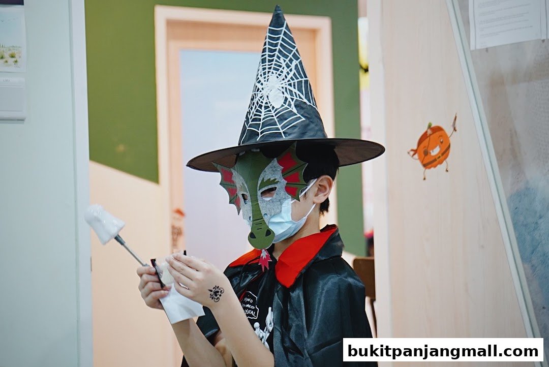 A child in a witch hat and dragon mask holds a wand and tissue.