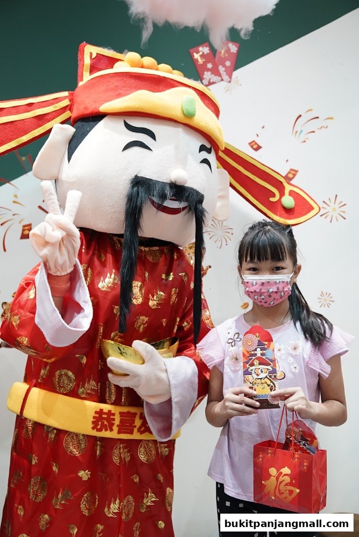 A child poses with a mascot dressed as a Chinese deity, holding gifts.