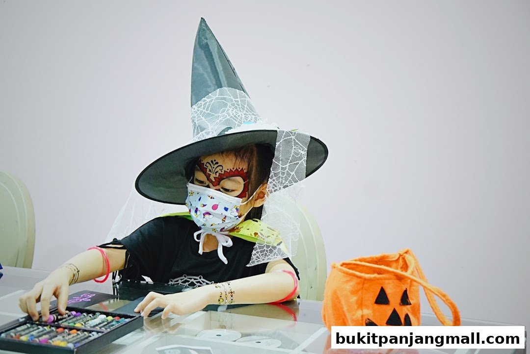 A child in a witch hat and face paint is preparing for Halloween.