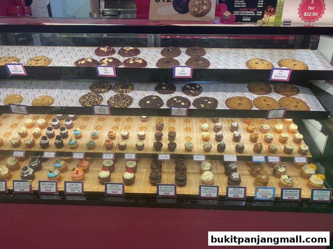 A display case filled with a variety of cupcakes and cookies from Twelve Cupcakes.