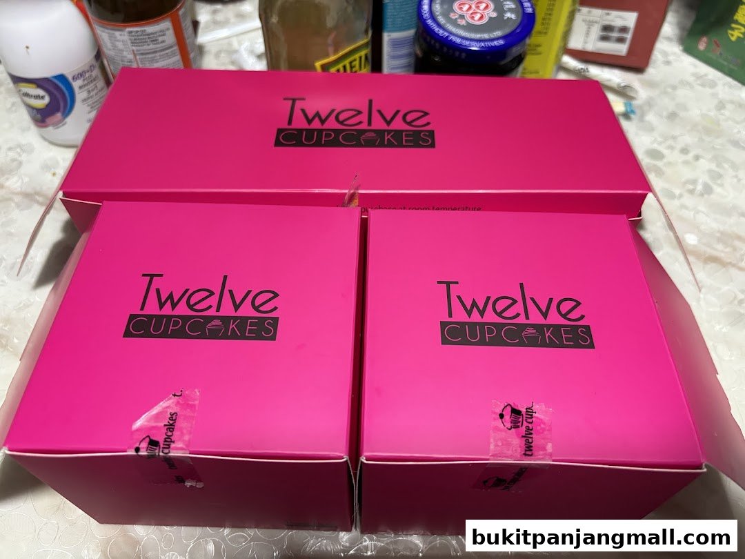 Bright pink boxes from Twelve Cupcakes, some open, revealing the brand's logo.