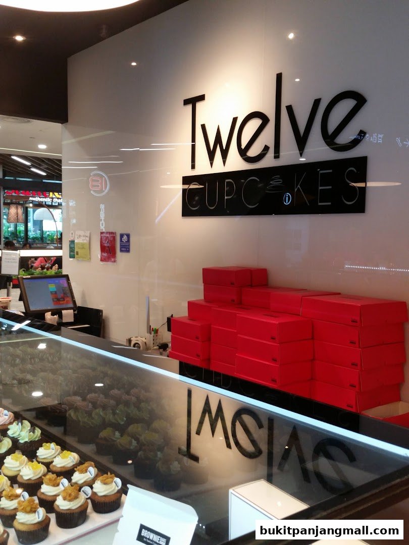 A display of cupcakes in a shop with the brand name 'Twelve Cupcakes' visible.