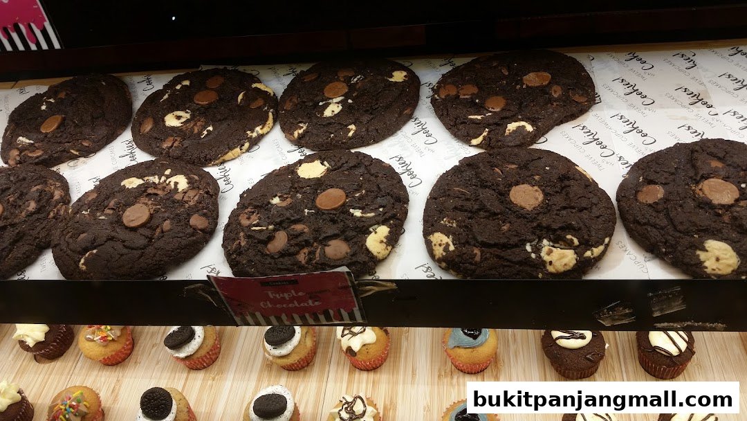 A display of freshly baked chocolate chip cookies and assorted cupcakes.
