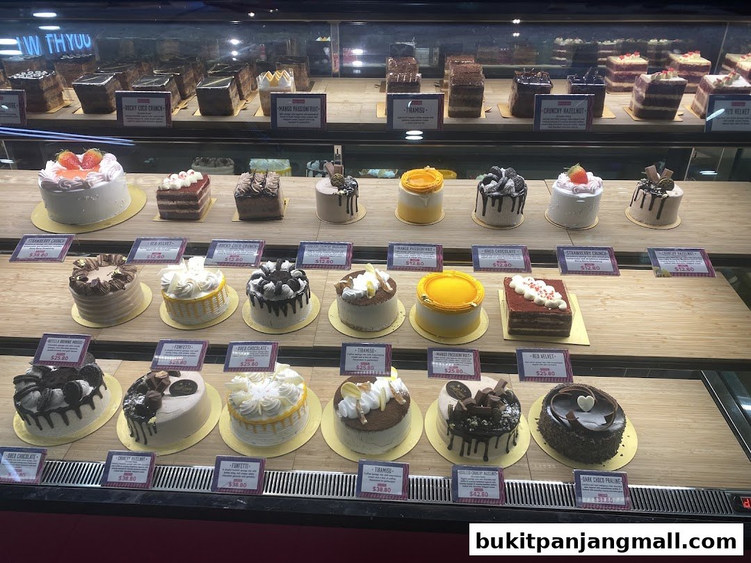A display case filled with a variety of beautifully decorated cupcakes and small cakes.