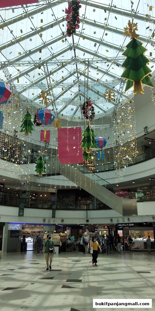 A shopping mall interior decorated with festive Christmas trees and lights.