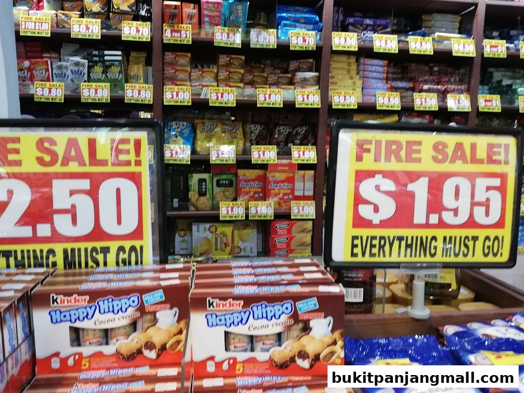 A retail shop interior displaying various snacks and promotional sale signs.