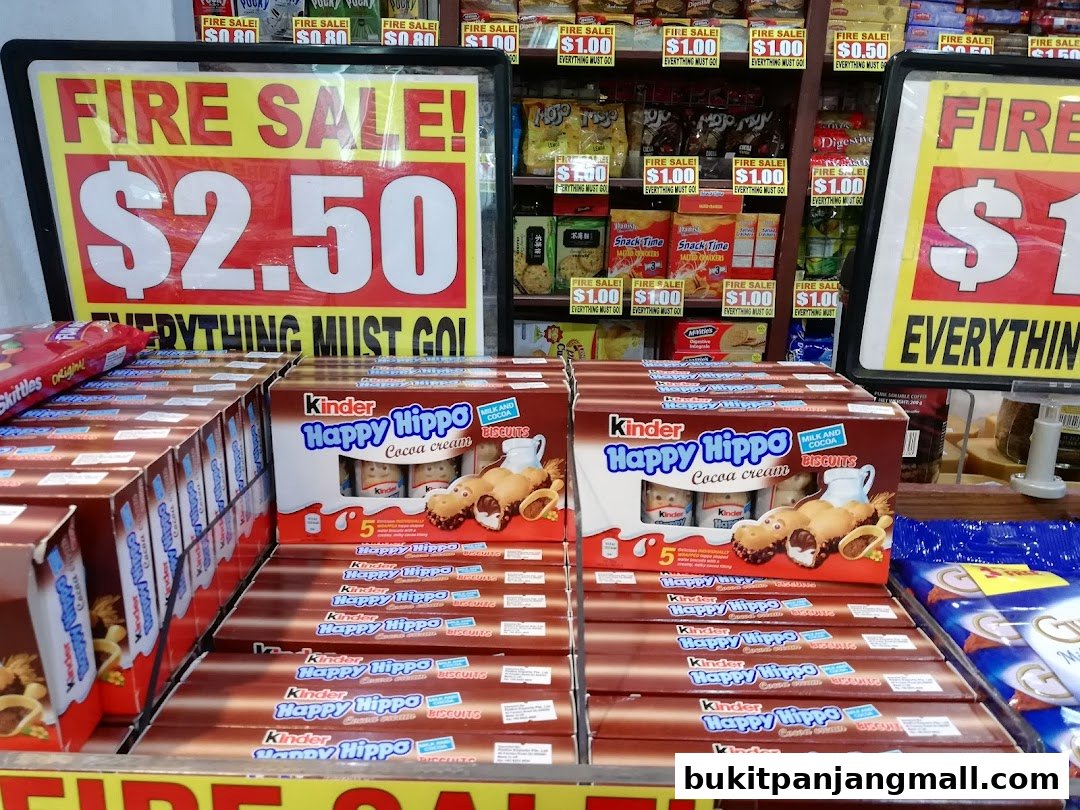 A retail store display featuring 'Fire Sale!' signs and boxes of Kinder Happy Hippo biscuits.