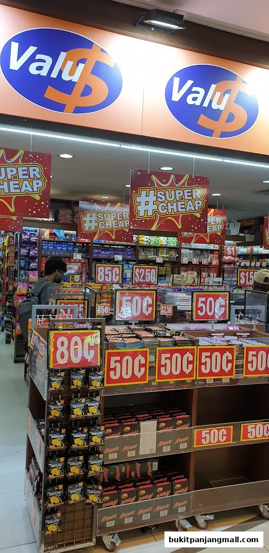 A retail store interior with shelves stocked with various products and prominent price signage.