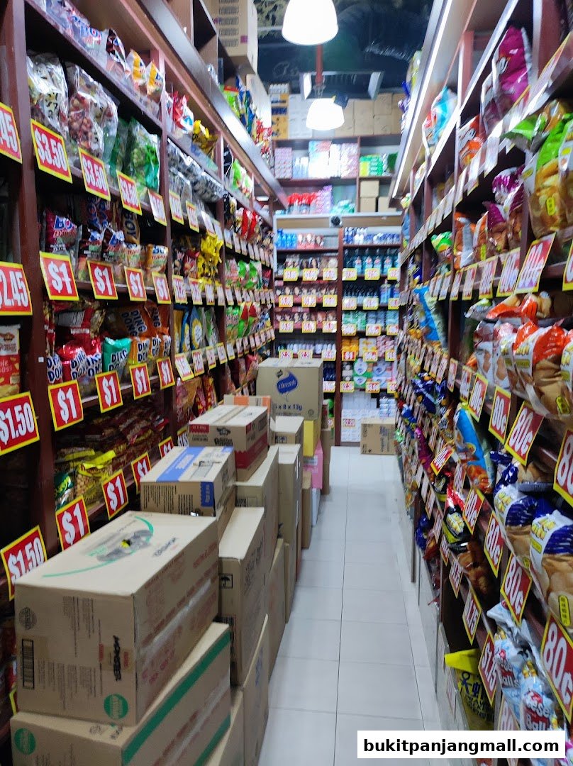 Aisle of a convenience store stocked with snacks and beverages, with price tags visible.