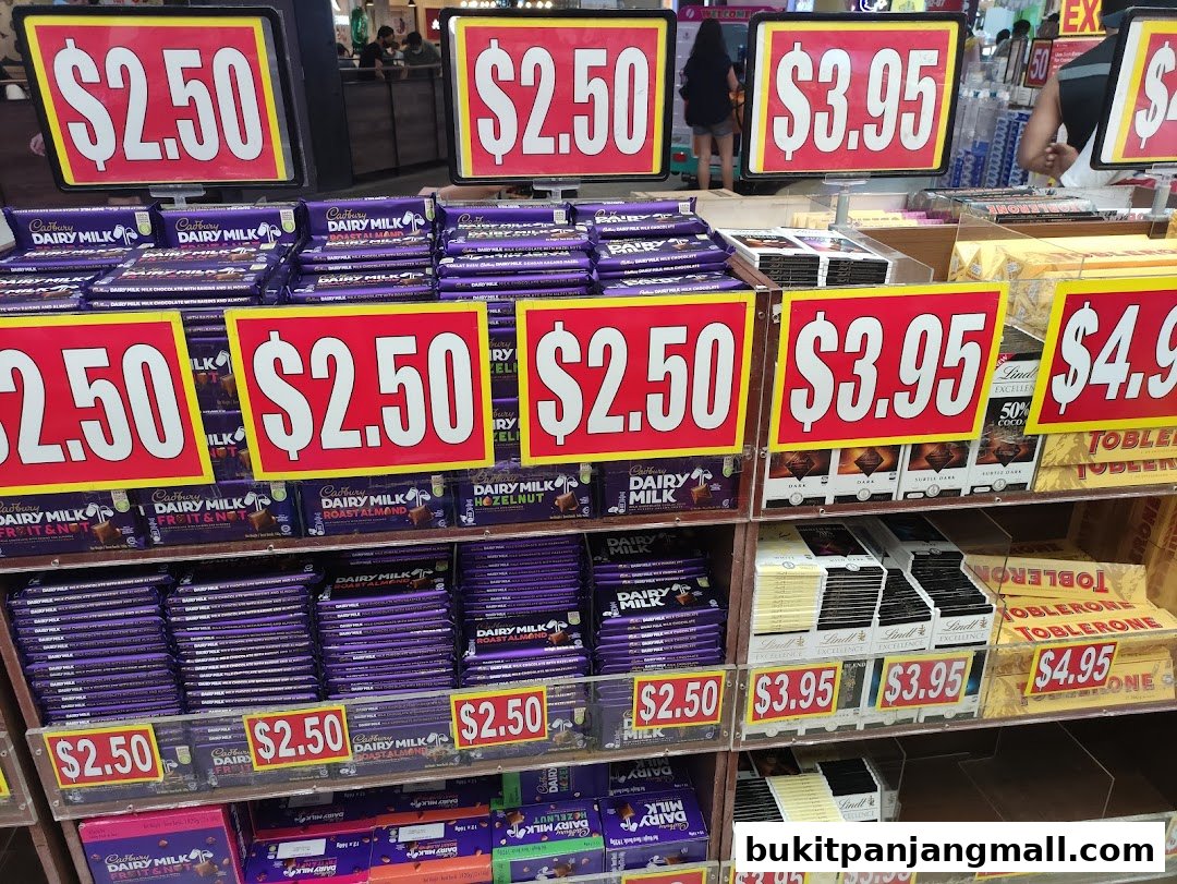 Shelves stocked with various chocolate bars, including Cadbury Dairy Milk and Toblerone, with price tags displayed.