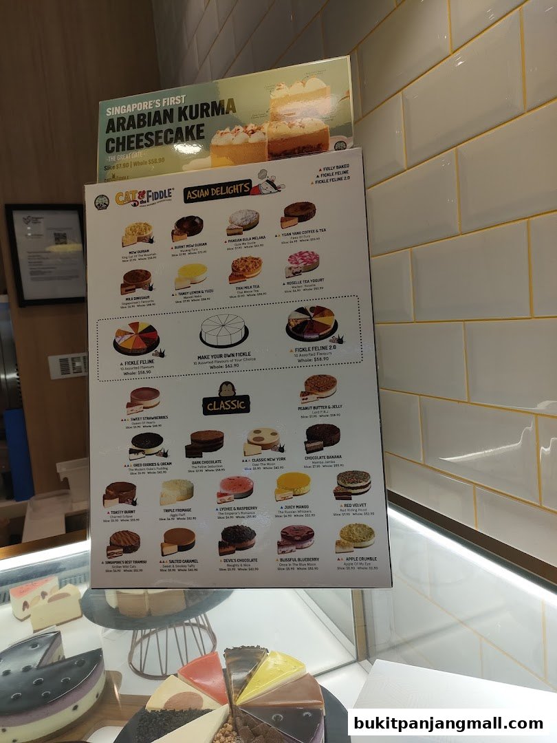 A menu board displays various cakes and cheesecakes with prices and descriptions.