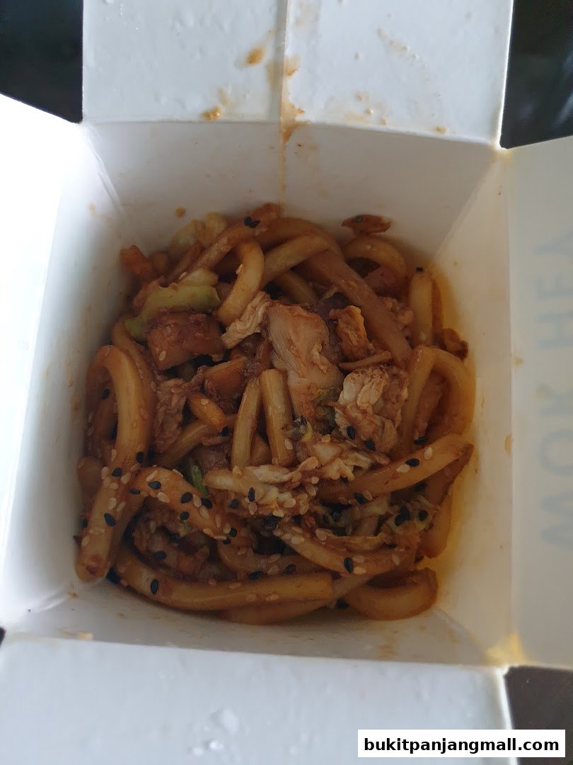 A close-up view of a takeaway box filled with delicious stir-fried noodles and chicken.