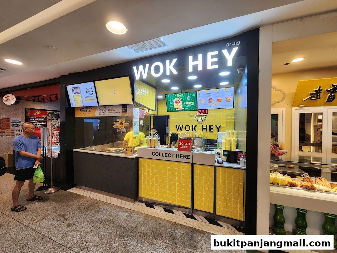The Wok Hey shop front with bright yellow tiles and digital menus displaying food.