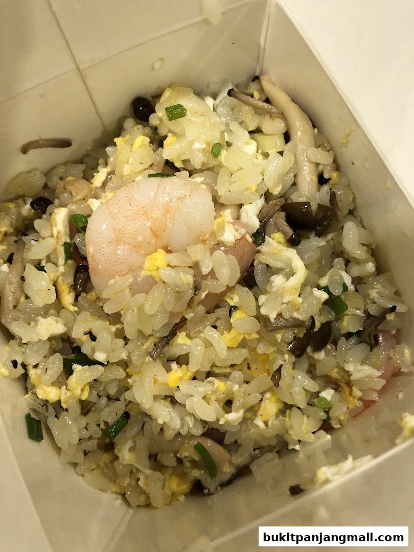 A close-up shot of a takeaway box filled with delicious fried rice, featuring shrimp and mushrooms.